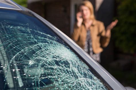 Cracked windshield with driver calling for service in the background